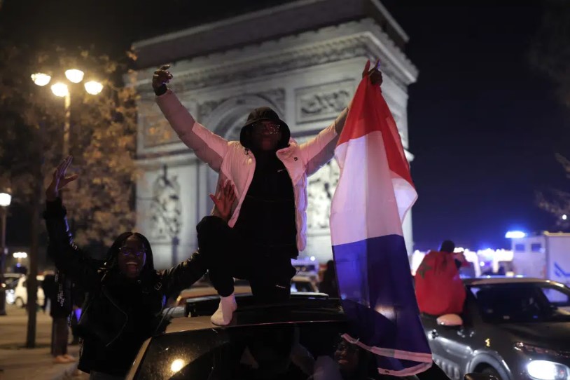 Pendukung Prancis merayakan kemenangan Prancis dengan mengibarkan bendera Prancis di Arc de Triomphe usai pertandingan sepak bola semifinal Piala Dunia antara Prancis dan Maroko, Rabu, 14 Desember 2022 di Paris. Prancis mengalahkan Maroko 2-0 dan akan menuju pertandingan perebutan gelar hari Minggu melawan Argentina. (Lewis Joy)